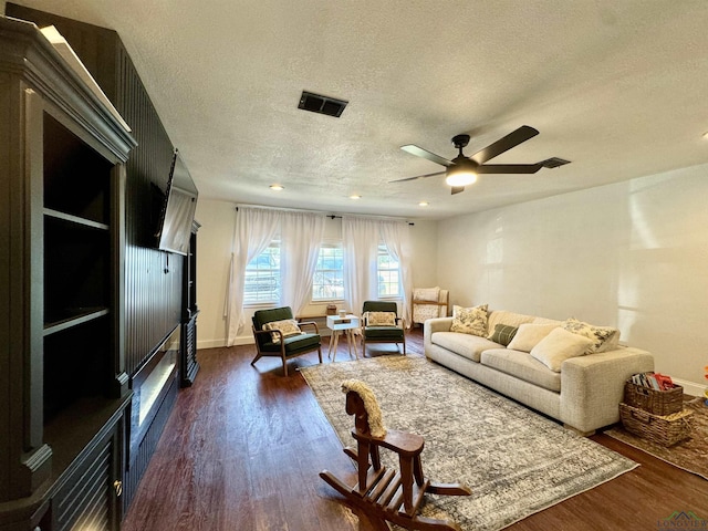 living room featuring ceiling fan, dark wood-type flooring, and a textured ceiling