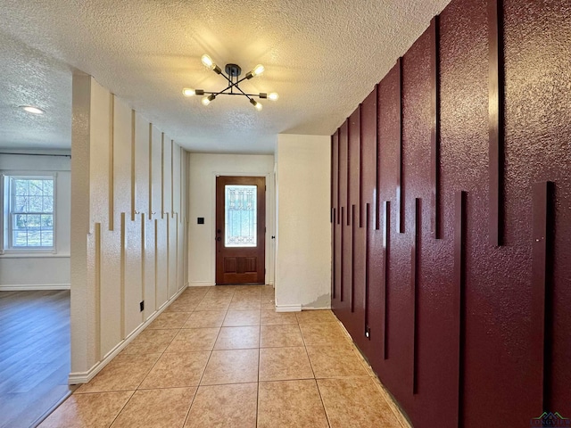 entryway with an inviting chandelier, a textured ceiling, and light tile patterned flooring