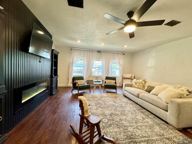 living room with dark hardwood / wood-style flooring, ceiling fan, and a textured ceiling