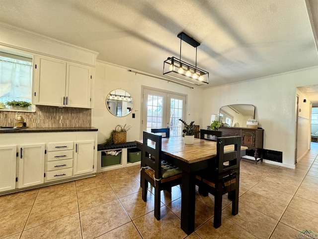 tiled dining area with crown molding, french doors, and a textured ceiling