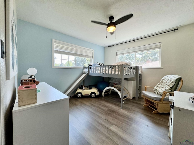 bedroom with a textured ceiling, ceiling fan, and hardwood / wood-style flooring