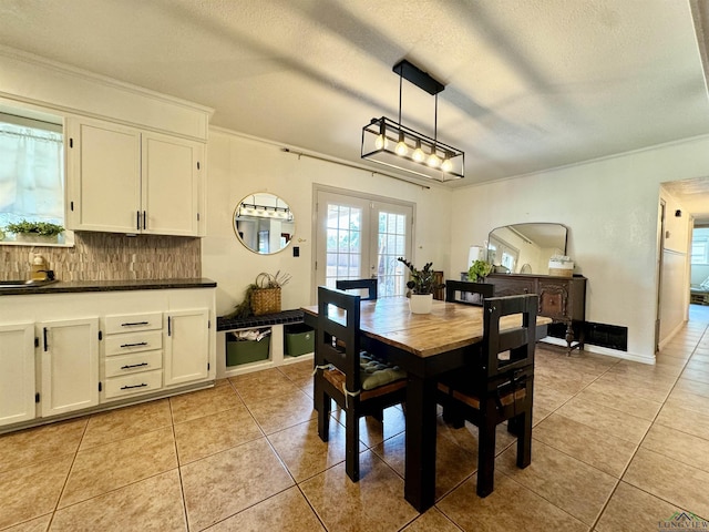 tiled dining space featuring french doors, ornamental molding, and a textured ceiling