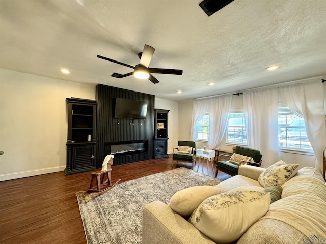 living room featuring ceiling fan, a textured ceiling, a fireplace, and dark hardwood / wood-style flooring