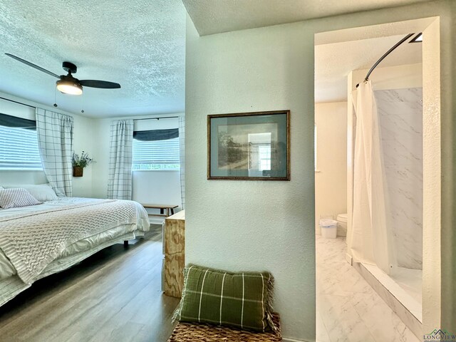 bedroom with ceiling fan, ensuite bathroom, and a textured ceiling