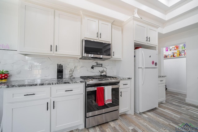 kitchen with light wood finished floors, stainless steel appliances, stone counters, and white cabinets