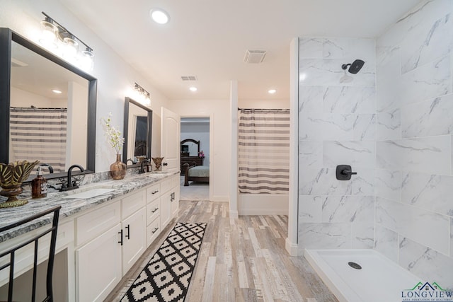 full bathroom featuring curtained shower, double vanity, wood finished floors, visible vents, and a sink