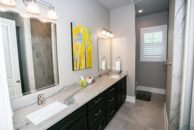 full bathroom with baseboards, double vanity, a sink, and toilet