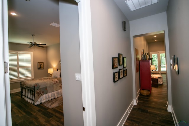 hall featuring baseboards, visible vents, and wood finished floors