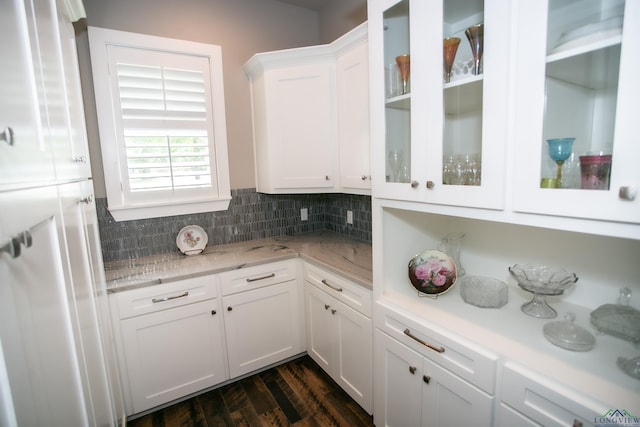 kitchen featuring light stone counters, backsplash, glass insert cabinets, white cabinets, and dark wood-type flooring
