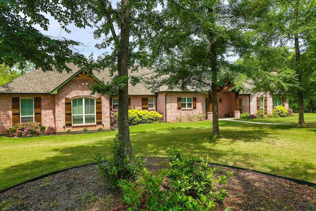 view of front of home with a front lawn, a shingled roof, and brick siding