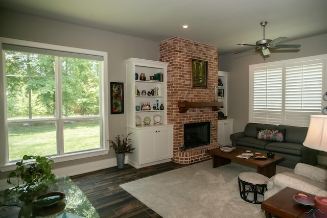 living room featuring plenty of natural light, a fireplace, dark wood-type flooring, and a ceiling fan