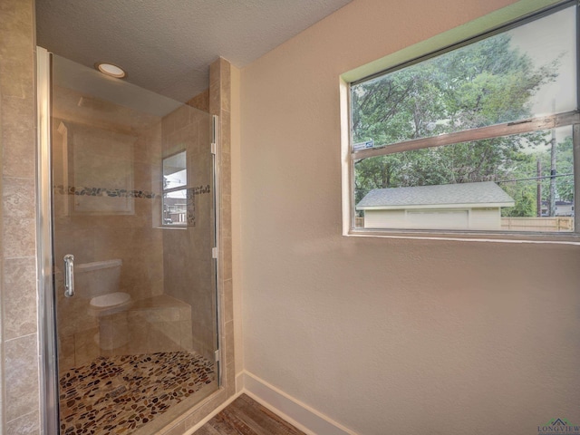 3902 Hazel St, Texarkana, TX 75503 - full bath with baseboards, plenty of natural light, a shower stall, wood finished floors, and a textured ceiling