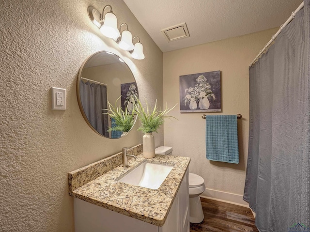 3902 Hazel St, Texarkana, TX 75503 - full bathroom featuring wood finished floors, toilet, vanity, a textured wall, and baseboards