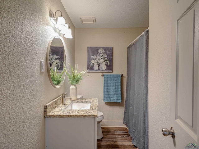 3902 Hazel St, Texarkana, TX 75503 - bathroom featuring wood finished floors, toilet, vanity, baseboards, and a textured wall