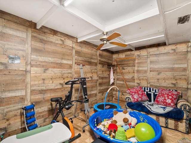 rec room with parquet flooring, beam ceiling, ceiling fan, and wooden walls