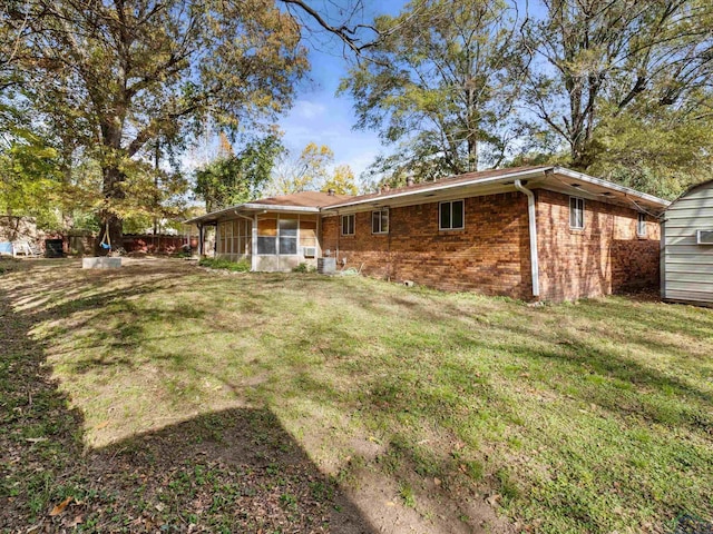 back of house featuring a lawn and a sunroom