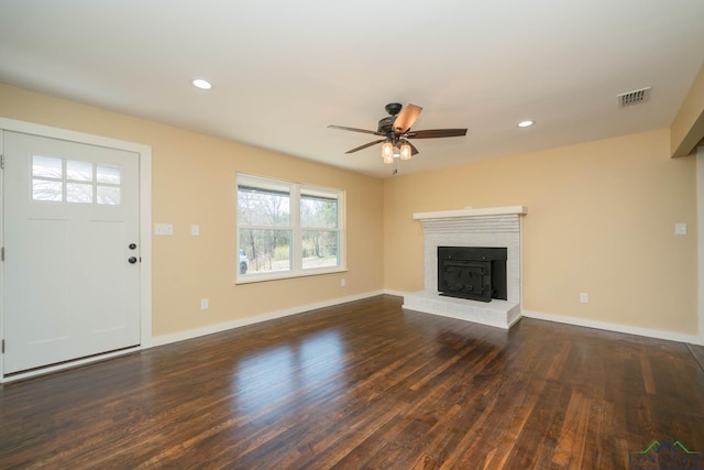 unfurnished living room featuring dark wood-type flooring, ceiling fan, and a brick fireplace