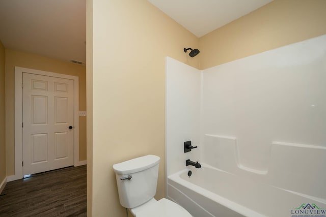 bathroom featuring bathing tub / shower combination, wood-type flooring, and toilet