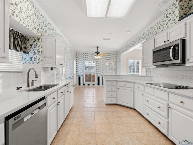 kitchen with stainless steel appliances, white cabinetry, ceiling fan, and sink