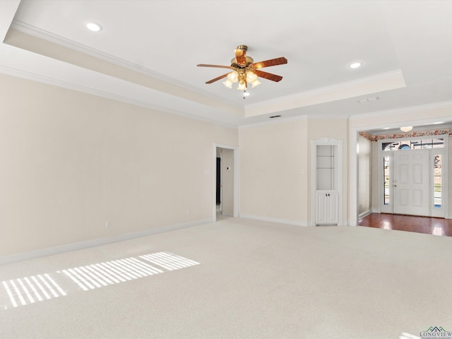 carpeted empty room with ceiling fan, crown molding, and a tray ceiling