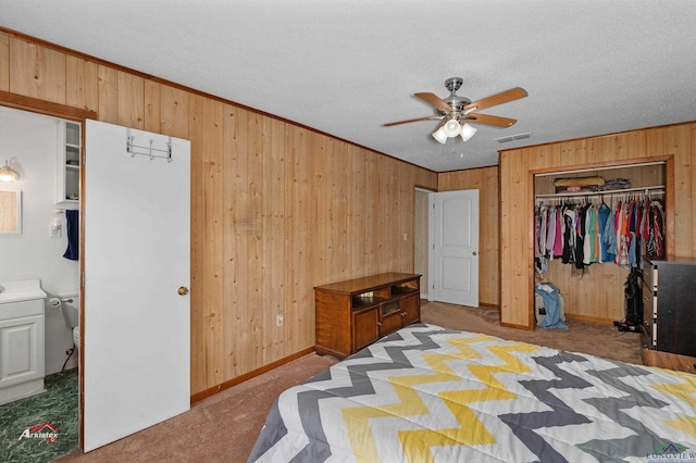 carpeted bedroom with ensuite bath, ceiling fan, a textured ceiling, a closet, and ornamental molding