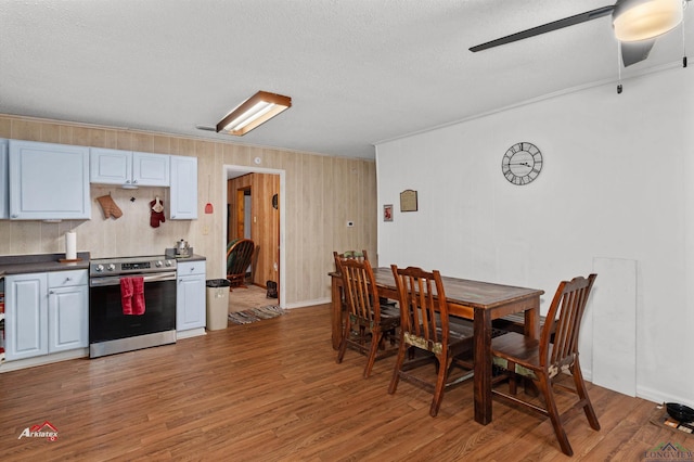 dining space with a textured ceiling, dark hardwood / wood-style floors, ceiling fan, and crown molding