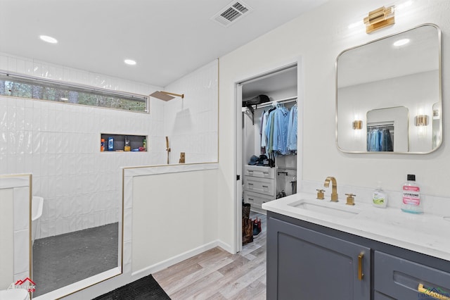 bathroom featuring tiled shower, vanity, and wood-type flooring