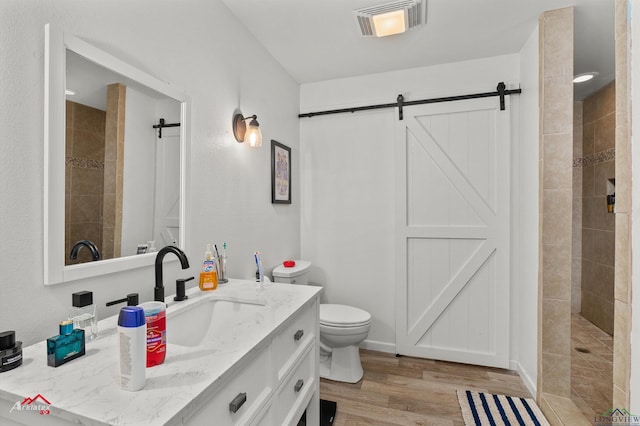 bathroom featuring tiled shower, vanity, toilet, and hardwood / wood-style floors