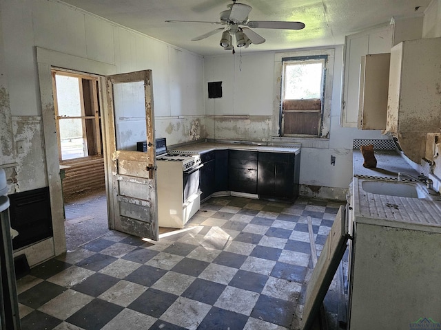 kitchen with white cabinets, ceiling fan, white gas stove, and sink