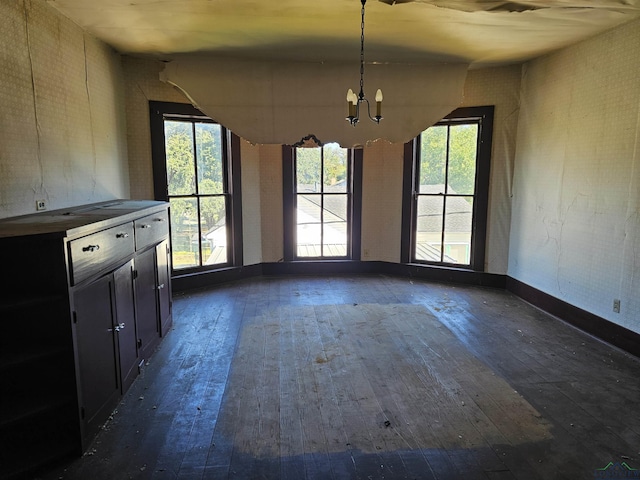 unfurnished dining area with dark hardwood / wood-style flooring and a notable chandelier