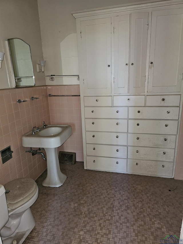 bathroom with toilet and tile walls