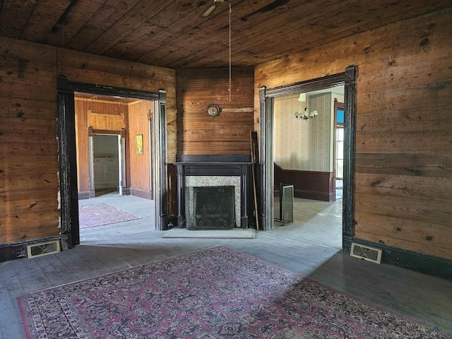 unfurnished living room with a multi sided fireplace, wood walls, wood ceiling, and wood-type flooring