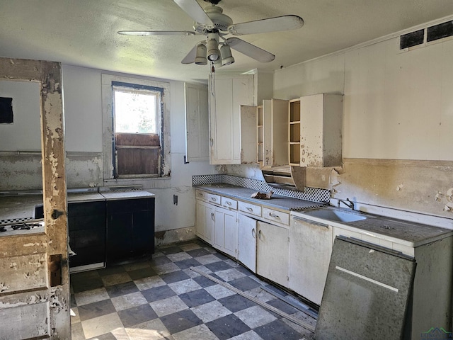 kitchen featuring a textured ceiling, white cabinetry, ceiling fan, and sink