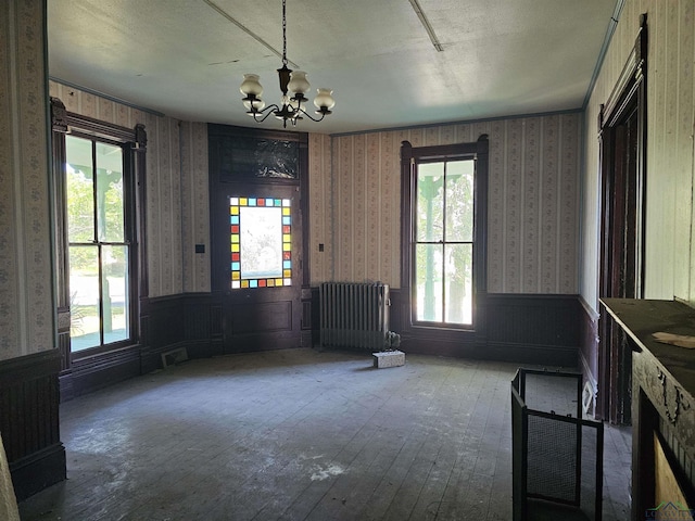 interior space with hardwood / wood-style floors, a notable chandelier, a textured ceiling, and radiator