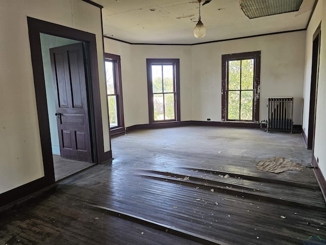 empty room featuring dark hardwood / wood-style floors, radiator, and ornamental molding