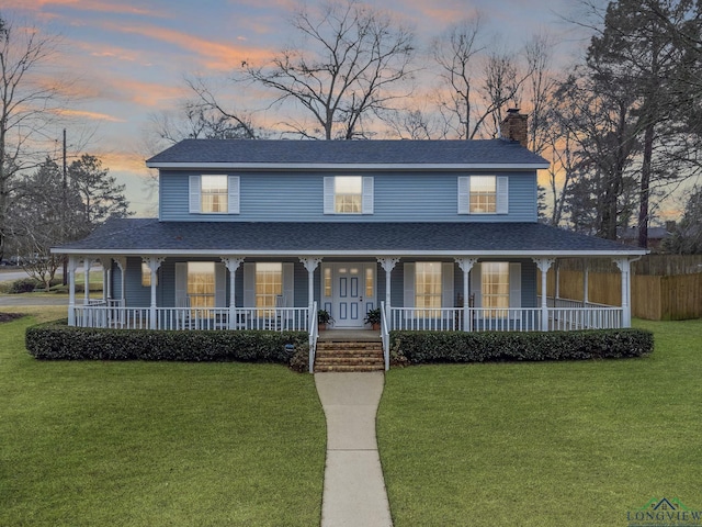 country-style home with covered porch, a shingled roof, and a front lawn