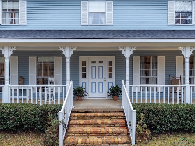 property entrance with a porch and roof with shingles