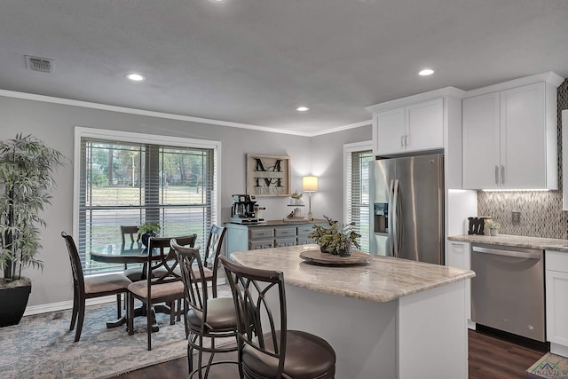 kitchen with white cabinetry, crown molding, a center island, and appliances with stainless steel finishes