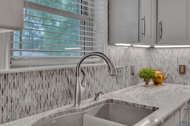 details featuring sink, decorative backsplash, and light stone countertops