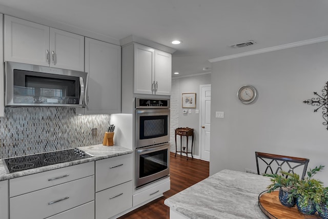 kitchen with white cabinetry, crown molding, dark hardwood / wood-style flooring, stainless steel appliances, and backsplash