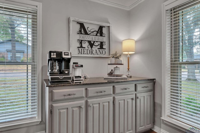 bar featuring white cabinetry, a healthy amount of sunlight, and crown molding