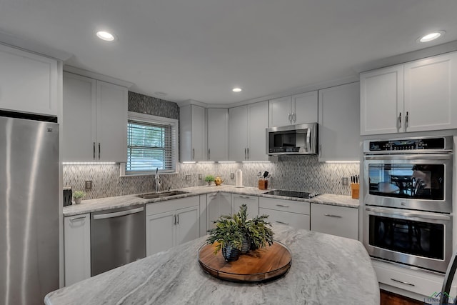 kitchen featuring light stone counters, stainless steel appliances, sink, and white cabinets