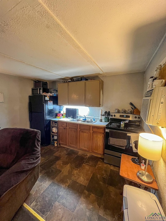 kitchen with black refrigerator, a textured ceiling, stainless steel electric range oven, and sink