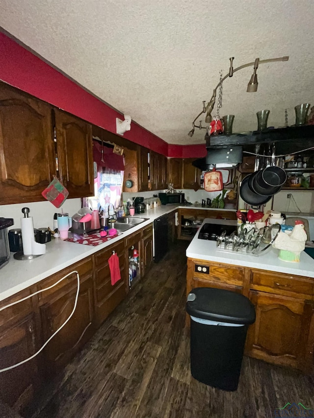 kitchen featuring dark brown cabinets, dishwasher, dark hardwood / wood-style flooring, sink, and a textured ceiling