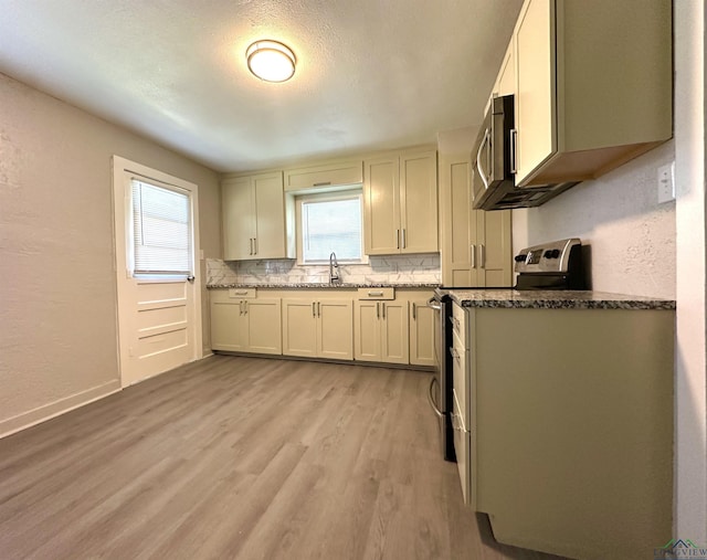 1407 E US-80, White Oak, TX 75693 - kitchen with stainless steel appliances, decorative backsplash, light wood-style floors, a sink, and stone counters