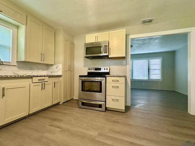 1407 E US-80, White Oak, TX 75693 - kitchen featuring stainless steel appliances, light wood-style flooring, decorative backsplash, and baseboards