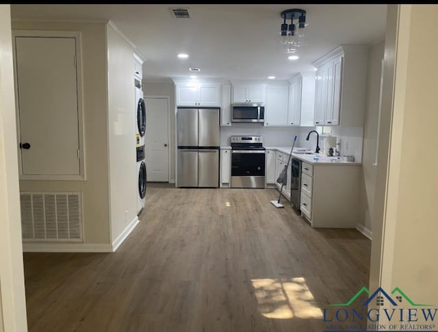 kitchen with a sink, visible vents, stacked washer / drying machine, and stainless steel appliances