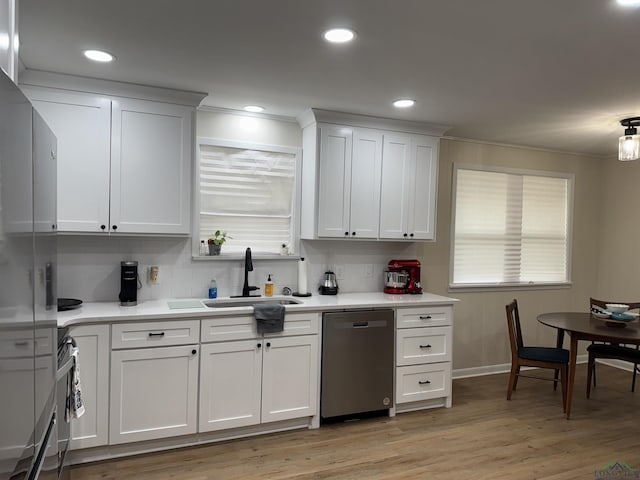 kitchen featuring a sink, light countertops, light wood-style floors, and stainless steel dishwasher