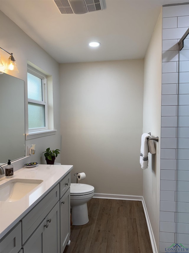 bathroom with visible vents, toilet, wood finished floors, baseboards, and vanity