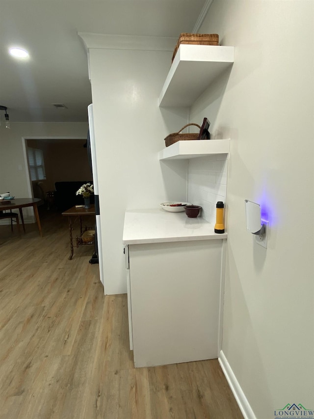 corridor featuring light wood finished floors, visible vents, and baseboards